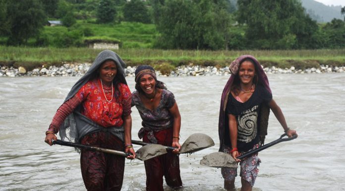 नदीबाट बालुवा निकाल्दै महिला ।